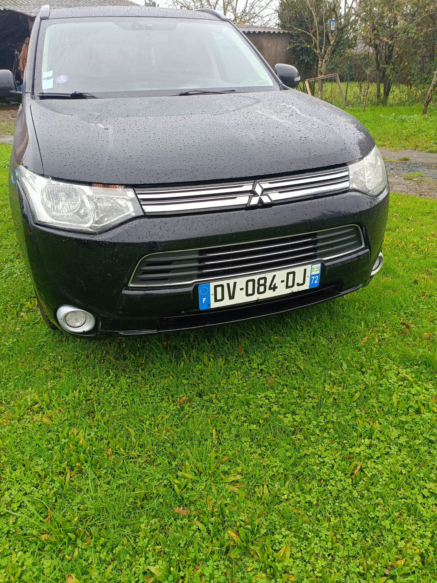 Vue rapprochée de l’avant du Mitsubishi Outlander PHEV noir, pare-chocs et phares sous la pluie